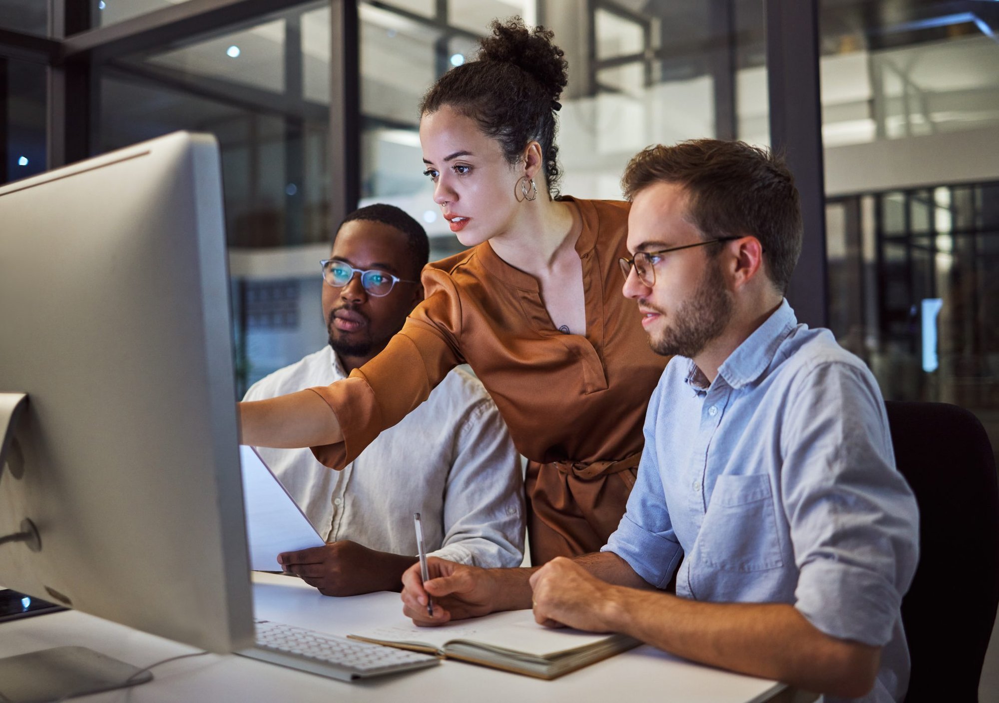 Female manager pointing at computer screen with two male colleagues to either side of her Female manager pointing at computer screen with two male colleagues to either side of her